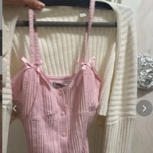 Söt ljusrosa ribbad linnetopp med rosetter - Supersöt ljusrosa linnetopp från F&F med ribbad struktur, smala axelband och små rosetter framtill. Toppen har dekorativa knappar i blomform längs framsidan och spetsdetaljer vid halsringningen. Perfekt för sommarens alla tillfällen! Säljer bara västen