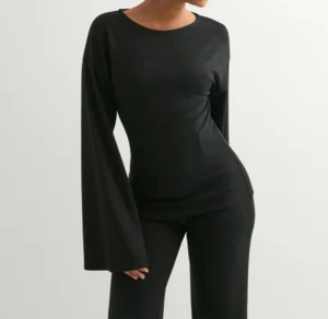 Svart långärmad topp från Nelly - Svart långärmad topp från Nelly med rund hals och riktigt snygga vida ärmar. Modellen är slim och sitter tajt över kroppen, vilket ger en clean och modern look. Perfekt att styla med jeans eller kjol för en cool vibe. är in storlek S, priset kan sänkas lite om ni vill köpa den för billigare så får ni gärna höra av er!😌 Den är andvänd ett par få gånger men innan jag skickar iväg den sp tvättar jag den! 