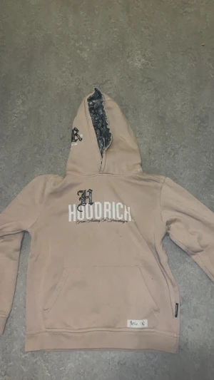 Beige hoodie från märket Hoodrich - En Hoodie från märket Hoodrich. Jag säljer den här hoodien i storlek 12- 13 years old så alla ungdomar som är i den åldern borde köpa denna.