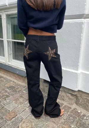 Svarta baggy jeans med leopard fickor  - Svarta baggy jeans med leopard fickor. Från design by si, har inte använts. Är hömidjade men man kan dra ner de så de blir mer baggy. köpte för 600 kr. 