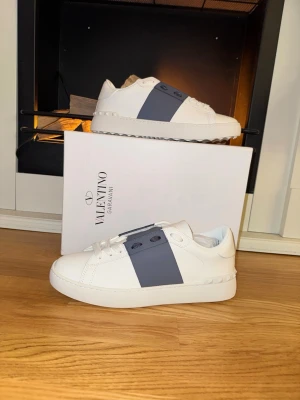 Valentino opens - Säljer nu ett par helt nya Valentino Opens. Dessa är i en grå/mörkblå färg med den klassiska vita basen. Strl 41. Utöver skorna får du oxå med alla tillbehör som syns på sista bilden. Bara att skriva ett DM vid intresse!