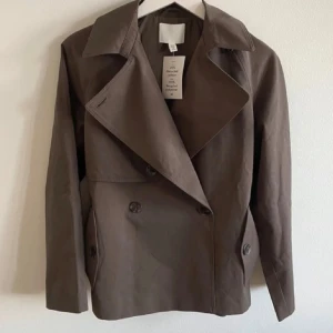 Brun kort trenchcoat med bälte - superfin trenchcoat från hm, slutsåld. Storlek xxs men den är stor i storlek så passar xs/s