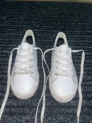 Sneakers - Vita sneakers från H&M med svart häl och pixelinspirerat mönster i svart, blått och vitt på sidorna. Skorna är unisex, i storlek 35 och inte jättemycket använda.