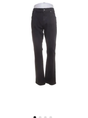 Svarta bootcut jeans från BOSS - Svarta jeans från BOSS med klassisk femficksdesign och bootcut-ben. Jeansen har hög midja och raka linjer, tillverkade i ett slitstarkt bomullsmaterial med en snygg svart ton. Perfekta för dig som gillar stilrena och tidlösa jeans.