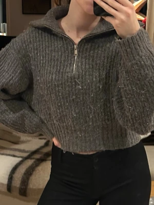 Grå ribbad stickad half zip tröja - Säljer en grå, ribbad och stickad tröja med half zip och hög krage. Modellen är lite croppad med långa ärmar och har en loose passform. Perfekt under höst och vinter. Storlek XS, från Gina Tricot