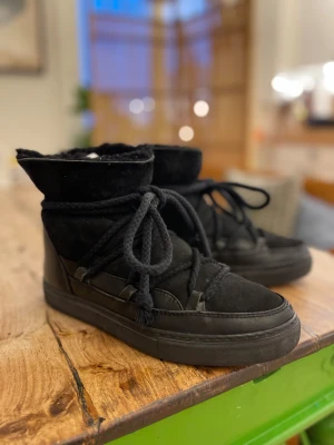 Svarta boots med snörning och mockadetaljer - Säljer ett par svarta boots med grov snörning och platt sula. Skorna har en kombination av mocka och skinn, samt högt skaft som ger en chunky vibe. Perfekta för kyligare dagar och passar till många olika outfits.