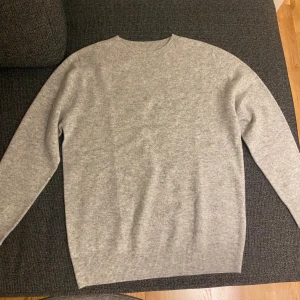 Ljusgrå tröja i Kashmir - En stilren ljusgrå kashmir tröja med rund halsringning och långa ärmar. Tröjan har en klassisk passform och är tillverkad i kashmir.  Perfekt för en clean look. (Aldrig använd)