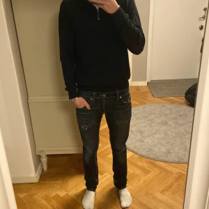 Mörkblå jeans från Dondup - Snygga mörkblå jeans från Dondup med slitningar och hål på framsidan för en cool, använd look. Klassisk femficksmodell med kontrastsömmar och metallnitar. Passformen är slim och midjan är låg. Perfekta för dig som gillar streetstyle och detaljer. Står att de är 31W i byxan men sitter mer som en 29. Längden på den är 32L