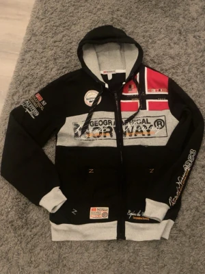 Svart Geographical Norway hoodie - Säljer en snygg hoodie i färgen svart från Geographical Norway! Använd 3-5 gånger och är i princip i nytt skick. Väldigt varm och skön, perfekt till alla årstider. 