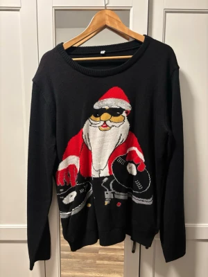 Svart jultröja  - Svart stickad jultröja/sweatshirt, ENDAST ANVÄND 1 GÅNG! Lyser med hjälp av den lilla kontrollen som har sitt eget fack inuti tröjan! Pm vid fler frågor! 