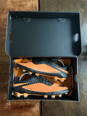 Nike Hypervenom fotbollsskor orange/svart - Säljer ett par Nike Hypervenom fotbollsskor i orange och svart. Storlek 44. Äkta köpt på unisport tillkommer låda och skopåse. Säljs billigare än vanligt pga en dobb har vässats ner rejält. Annars är skon i fint skick och har många matcher kvar 