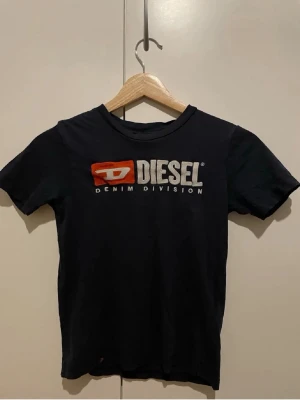 MARINBLÅ  t-shirt från Diesel - Säljer en marinblå t-shirt från Diesel med tryckt logga och texten 'Denim Division' i vitt och rött på bröstet. Har en jätte liten klorin fläck typ längst ner som ej är super synlig ❤️