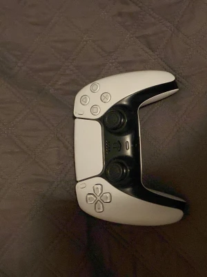 PlayStation 5 DualSense Wireless Controller - Säljer en PlayStation 5 DualSense trådlös handkontroll i vitt. Kontrollen är i gott skick med mindre tecken på användning. Perfekt för dig som vill ha en extra handkontroll till din PS5. Alla knappar och spakar fungerar som de ska.