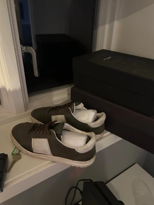 Valentino flycrew - Säljer ett par stilrena sneakers i olivgrönt och vitt med snörning. Skorna har en platt sula med unikt mönster undertill och är tillverkade i mocka och skinn. Perfekta för dig som gillar klassisk streetstil och vill ha något som sticker ut lite extra.