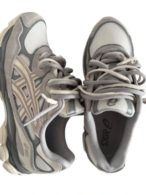 Asics gel nyc - Snygga sneakers från ASICS i olika grå nyanser med beige detaljer. Skorna har en sportig design med meshpaneler för bra ventilation och partier i skinn för extra hållbarhet. Klassisk snörning och platt sula gör dem perfekta för en aktiv livsstil. Pris kan diskuteras och fler bilder kan fixas om man vill det