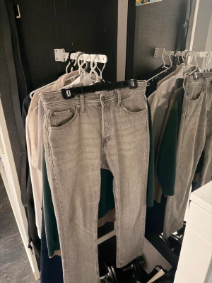 Grå ” Jack&Jones ” jeans  - Säljer ett par grå jeans från Jack&Jones med klassisk femficksdesign och ljus tvätt. Byxorna har rak passform och är tillverkade i slitstark bomull. Perfekt för dig som gillar stilrena och tidlösa jeans. Jeansen är i mycket bra skick! finns ett litet hål på vänster fickan .