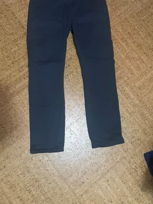 Chinos - Snygga mörkblå chinos från Lee med raka ben och klassisk passform. Byxorna har två bakfickor med knapp och en diskret Lee-logga ovanför fickan. Perfekta för en chill och stilren look. Materialet känns mjukt och bekvämt mot huden.