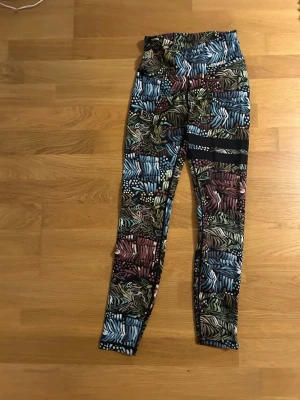 Mönstrade leggings från Stronger XS - Säljer ett par färgglada leggings från Stronger i storlek XS. De har ett coolt mönster med inslag av blått, grönt, vinrött och svart, samt zebrainspirerade detaljer. Säljer då den ej används.