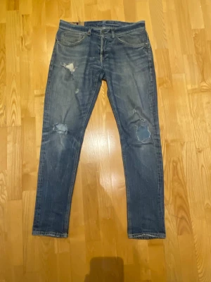 Dondup jeans  med slitningar - Säljer ett par blå jeans från Dondup med snygga slitningar på knäna. Modellen är George och skicket är ungefär 8/10. Hör av dig vid fler funderingar!