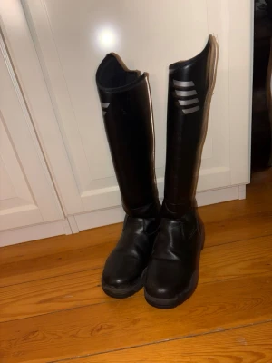 Svarta ridstövlar med dragkedja - Säljer ett par svarta ridstövlar från CRW med reflexer. Köp nu jag postar snabbt!!