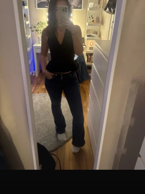 Mörkblå bootcut jeans - Säljer ett par mörkblå jeans med bootcut-snitt. Jeansen har klassisk femficksdesign, normal passform och är tillverkade i jeansmaterial. Midjan är midwaist och färgen är djup mörkblå, vilket ger en snygg och tidlös look.