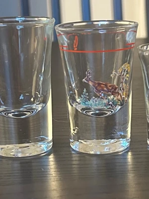 Blandade snapsglas - Ett set med snapsglas i olika utföranden. Inkluderar ett snapsglas med motiv av ett rådjur och en  äggkopp märkt S.T.
