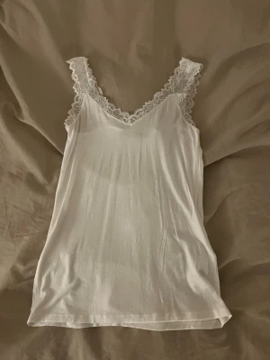 Vit spetskantad linnetopp Vero Moda - Säljer en vit linnetopp från Vero Moda i storlek M. Toppen har breda axelband med dekorativ spets och en v-ringad halsringning. den är köpt på nelly 🤍