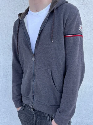Moncler zip hoodie - Säljer denna asfeta hoodie från Moncler! Skick 9/10 - Inga defekter. Nypris 6999kr, mitt pris endast 1199kr. Storlek XL, men passar M/L (modellen är 186 cm). Hör av er vid funderingar.