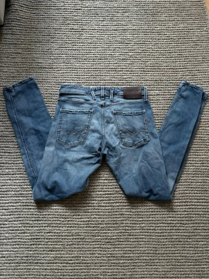 Replay Anbass  - Replay Anbass w 32 L 34 längd 106 cm midjemått 39x2 cm. Mycket fint skick men Anbass lappen har försvunnit men den sitter på insidan så det ser man inte. Snygga slitningar vid fickorna och en fräsch fade! Sitter slim!