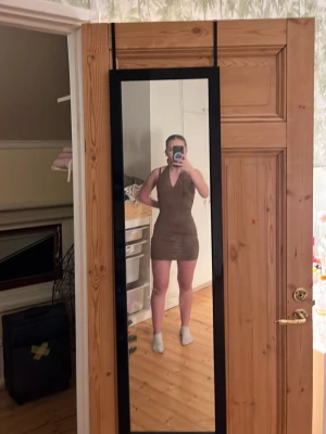 Brun tight kortklänning med v-ringning - Säljer en brun, tight och ärmlös kortklänning med v-ringad hals. Klänningen har en enkel och stilren design som framhäver figuren. Perfekt för dig som gillar minimalistisk stil och vill ha något bekvämt men ändå snyggt. Fråga mig om ni undrar något 😊