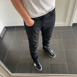 Tiger Of Sweden Jeans - Säljer ett par svarta jeans från Tiger Of Sweden i modellen Pistolero. Jeansen har klassisk femficksdesign, raka ben och normal passform. Snyggt läderpatch bak i midjan och diskreta detaljer. Perfekta till sneakers och t-shirt för en clean look.