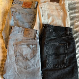Fyra par jeans i olika färger - Säljer fyra par jeans: ett par ljusblå Levi's 505 30/32, ett par beigea/vita Sweet SKTBS jeans W29, ett par ljusgrå Jack & Jones 32/30 och ett par svarta nudie jeans 31/32. Alla har klassisk femficksdesign och raka ben. Perfekta för dig som vill variera din stil med olika färger och märken. Hör av dig vid frågor och funderingar och pris