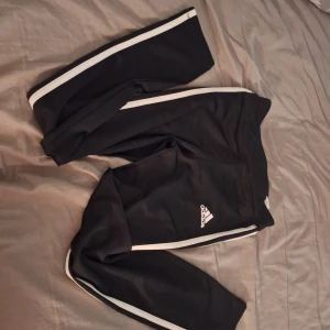 Adidas byxor - Svarta Adidas tights med Adidas Logan i vitt. Och de tre sträken på var sin sida av benen.