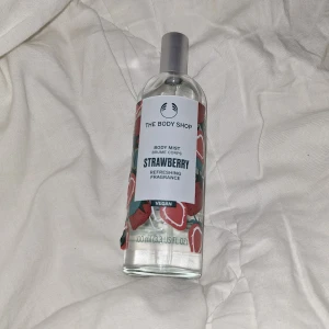 Strawberry Body Mist från The Body Shop - Fräsch body mist med jordgubbsdoft från The Body Shop. Flaskan är genomskinlig med ett färgglatt jordgubbsmönster och har en silverfärgad spraykork. Innehåller 100 ml och är vegansk. Perfekt för dig som älskar söta och fruktiga dofter. Använt bara nån gång, max 2 gånger.