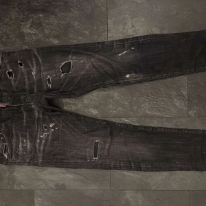 Dsquared2 jeans - Riktigt snygga svarta jeans från Dsquared2 med coola slitningar och hål för en edgy look. Jeansen har smal passform och klassisk femficksdesign. Tillverkade i bomull med en skön känsla och detaljerade slitningar över hela benen.