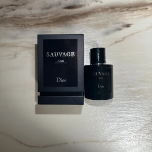 Dior Sauvage Elixir 100ml parfym - Dior Sauvage Elixir är en exklusiv herrparfym i en mörkblå, nästan svart, rund glasflaska med silverdetaljer. Flaskan rymmer 100 ml och kommer i en elegant svart kartong med tydlig logga. En lyxig och intensiv doft för dig som vill sticka ut.