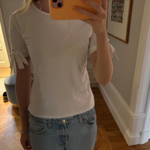 T-shirt med rosetter  - Så söt vit T-shirt med rosetter på ärmarna 🎀🎀