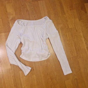 Vit ribbad långärmad topp - Säljer en vit ribbad topp med lång ärm och bred, något offshoulder ringning. Toppen är croppad och har en smickrande passform som sitter snyggt på kroppen. Perfekt att styla med jeans eller kjol för en clean look.