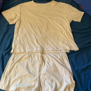 Beige ribbad pyjamas från Kappahl - Snygg beige pyjamas från Kappahl i ribbat material. Den har en relaxed fit och elastisk midja med snörning för extra komfort. Perfekt för varma dagar eller som chill-plagg hemma.