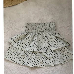 Prickig volangkjol från Seaside - Supersöt kort volangkjol från Seaside i vitt med svarta prickar. Kjolen har smock i midjan för en bekväm passform och dubbla volanger som ger en extra snygg look. Perfekt för dig som gillar trendiga plagg. Aldrig använt🤍