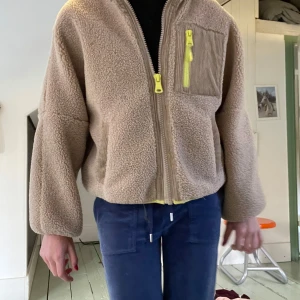 Beige teddyjacka från ZARA med neon-detaljer - Säljer en beige teddyjacka från ZARA med coola neon-gula dragkedjor och foder. Jackan har en bröstficka i manchester, två sidofickor och oversized passform. Den är en perfekt höstjacka och lite kortare i modellen. Verkligen så så fin och unik!! 