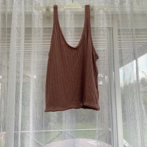 RödBrun ribbad linnetopp - Säljer en brun ribbad linnetopp med djup urringning och ärmlös design. Toppen är croppad och har en enkel, stilren look som passar perfekt till varma dagar eller lager på lager-stil. Den är stor vid bysten och jag har storlek 75B 