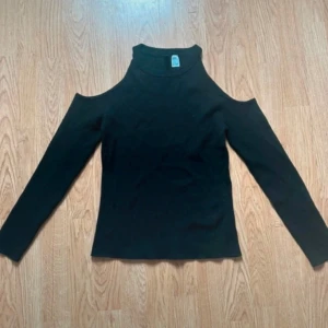 Svart långärmad topp med cold shoulder - Svart långärmad topp från H&M med trendig cold shoulder-design och hög hals. Toppen är ribbad och har en slim passform