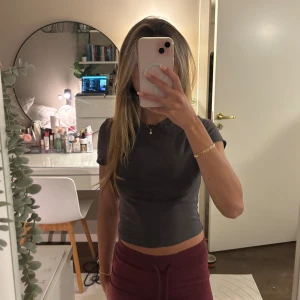 Mörkgrå croppad topp - Säljer en enkel och stilren mörkgrå croppad topp med korta ärmar. Toppen har en tight passform och är perfekt att matcha med höga byxor eller kjol. Materialet känns mjukt och stretchigt, vilket gör den superbekväm att bära. Hör av dig om du har några frågor! 🫶🏼💕