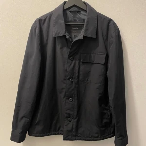 Marinblå jacka från Massimo Dutti - Säljer en stilren marinblå overshirt/jacka från Massimo Dutti. Jackan har en klassisk krage och knäppning framtill med knappar. Passar bra till höst och vår. Oanvänd i nyskick, nypris 1390.