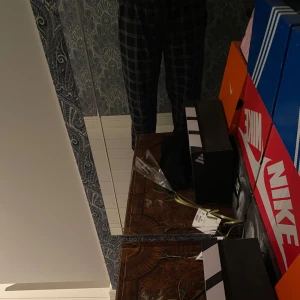 Svarta rutiga mjukisbyxor med snörning - Säljer ett par svarta mjukisbyxor med vitt rutmönster och dragsko i midjan. Byxorna har en relaxed fit och resår i midjan för extra komfort. Perfekta för chill dagar hemma eller när du vill vara bekväm men ändå se snygg ut.