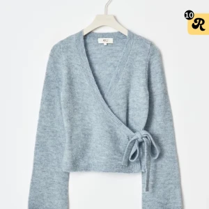 Slut sålda wrap tröjan Gina tricot - Supermysig ljusblå omlottstickad topp från Monki med v-ringning och knyt i sidan. Croppad modell med långa ärmar och mjukt material som känns skönt mot huden. Perfekt för att ge din outfit en chill vibe.