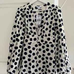 Vit kortklänning med svarta prickar från Next - Superfin kortklänning från Next i vit med stora svarta prickar. Helt ny oanvänd, med prislapp, endast testad. Som en adoore klänning i modellen, storlek 36. Säljer för 350kr