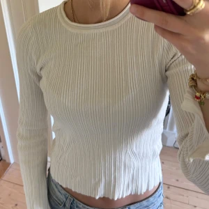 Vit ribbad blus från Neo Noir - Säljer en vit ribbad blus från Neo Noir i storlek 34. Blusen har långärmade ärmar, rund halsringning och är tillverkad i en mjuk mix av viskos och nylon. Snygg passform som sitter tajt och ger en clean look. 