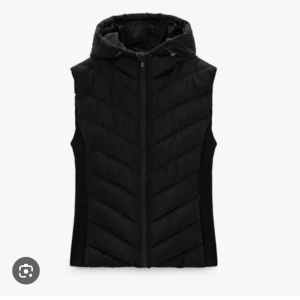 !BUDA! Svart dunväst med huva - Snygg svart dunväst med huva och dragkedja framtill. Västen har en quiltad design med diskreta diagonala sömmar och en sportig look. Perfekt att slänga över en hoodie eller tröja när det är kyligt ute.